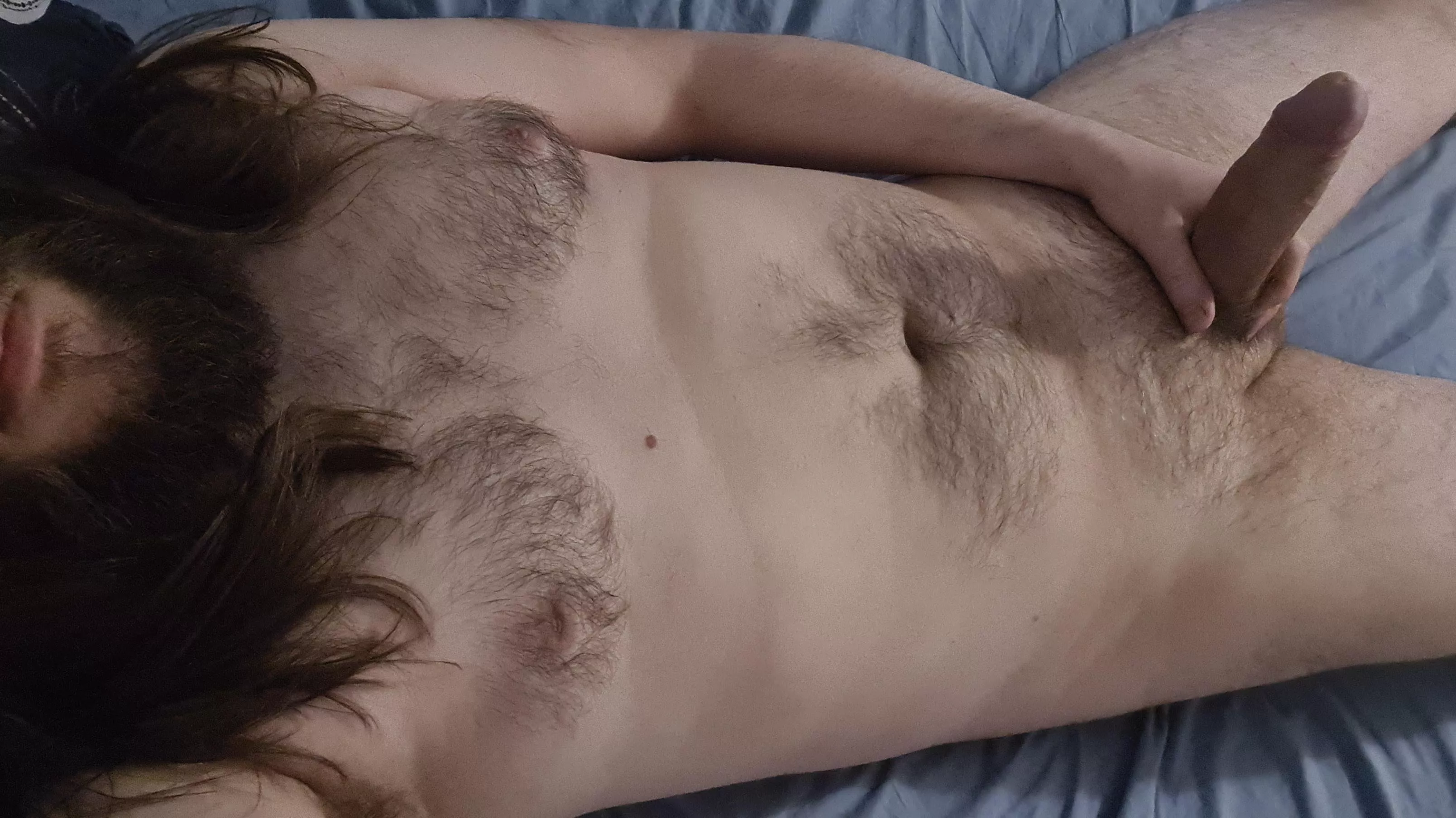 Bearded guy laying down with erect cock pointing upwards