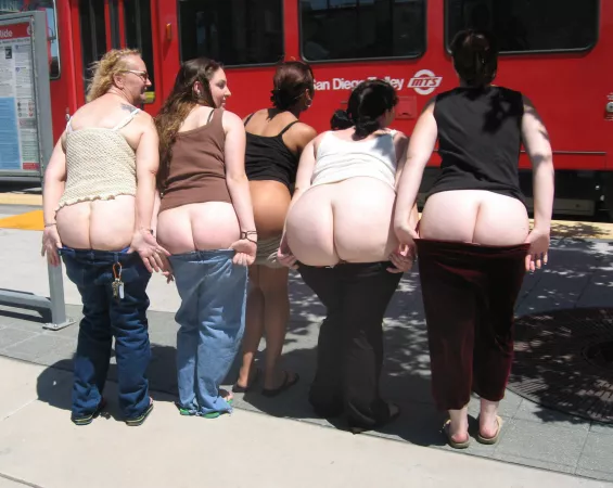 Big group of friends mooning next to train