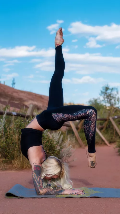 Blonde yoga girl Brittany with tattoos and legs for days. One legged wheel pose.