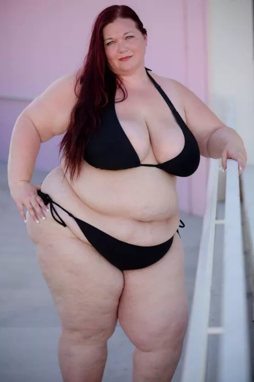 Plump and pale redhead in a black bikini