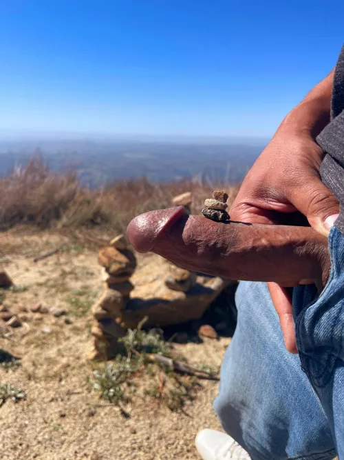 Rock stacking and cock flashing atop a mountain.