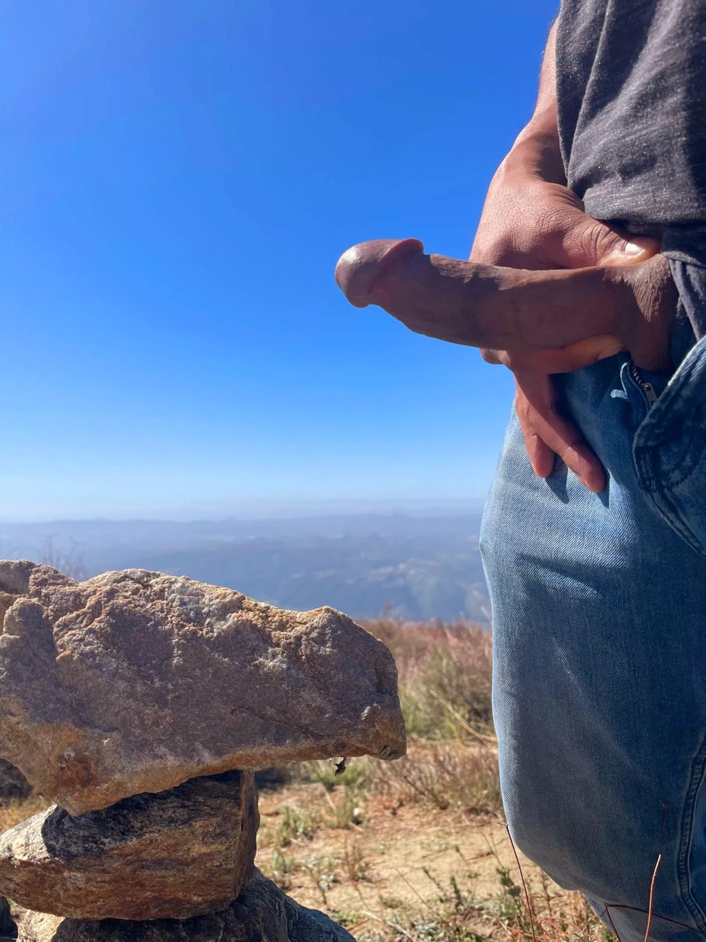Rock stacking and cock flashing atop a mountain.