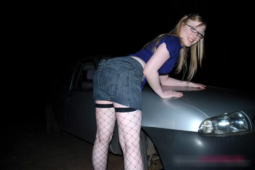 Satine Spark bent over a car in the dark Satine Spark bent over a car in the dark