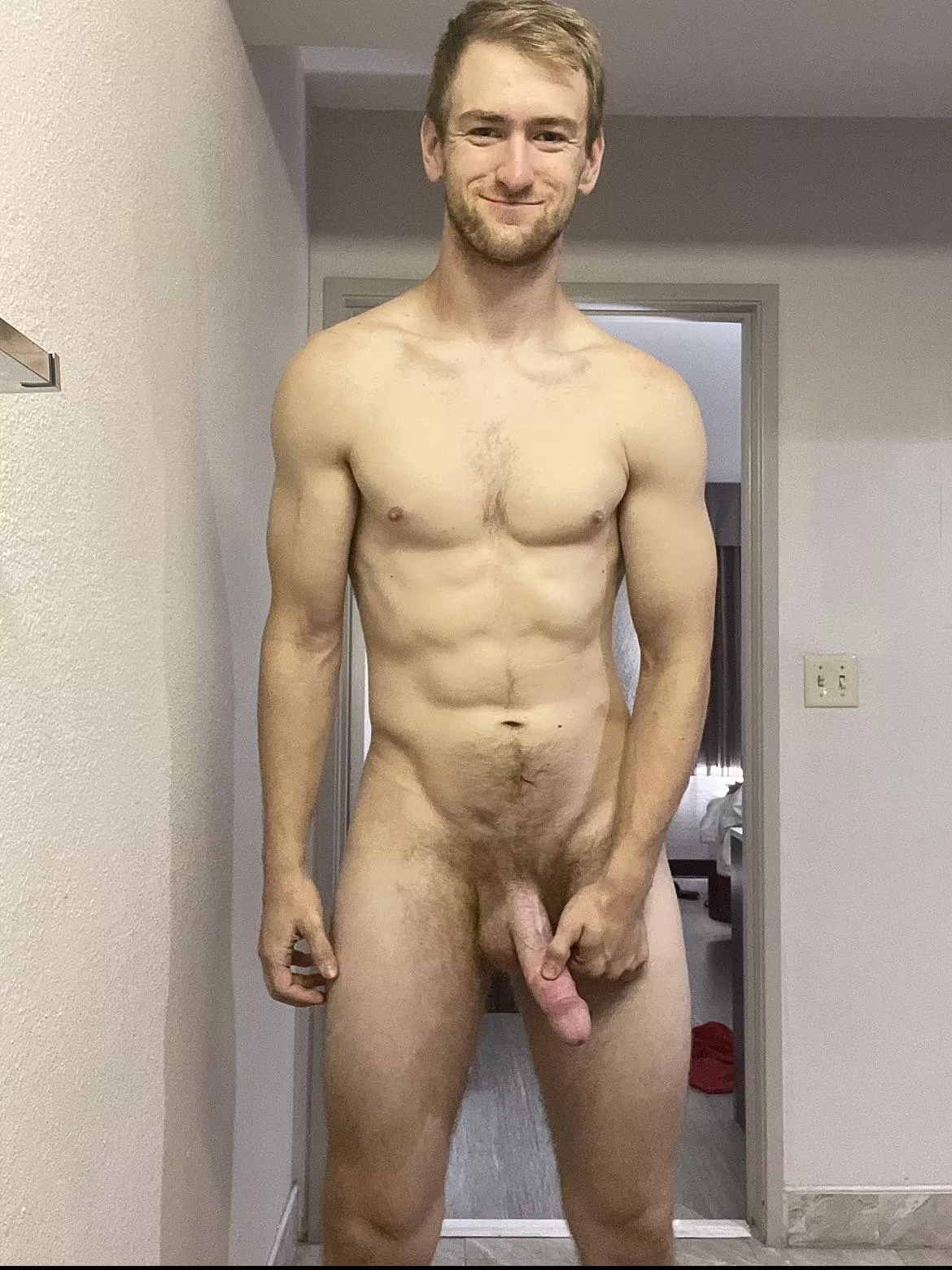 Tall drunk man happily grabbing penis in hotel