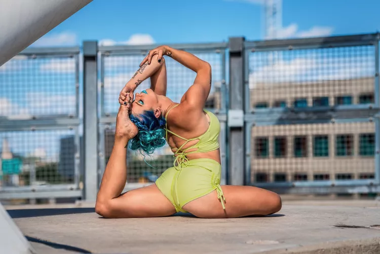 Yoga girl in a urban landscape doing a one-legged king pigeon pose.